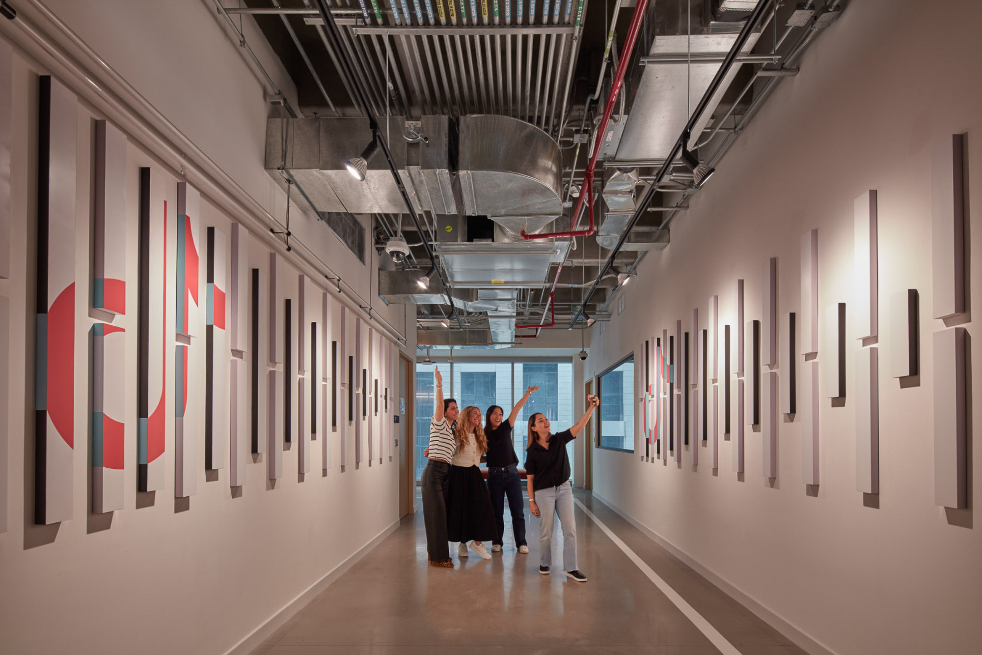 A group of people standing in a hallway with a wall of art.