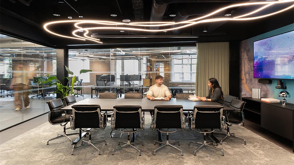 A man and woman sitting at a table in a conference room.