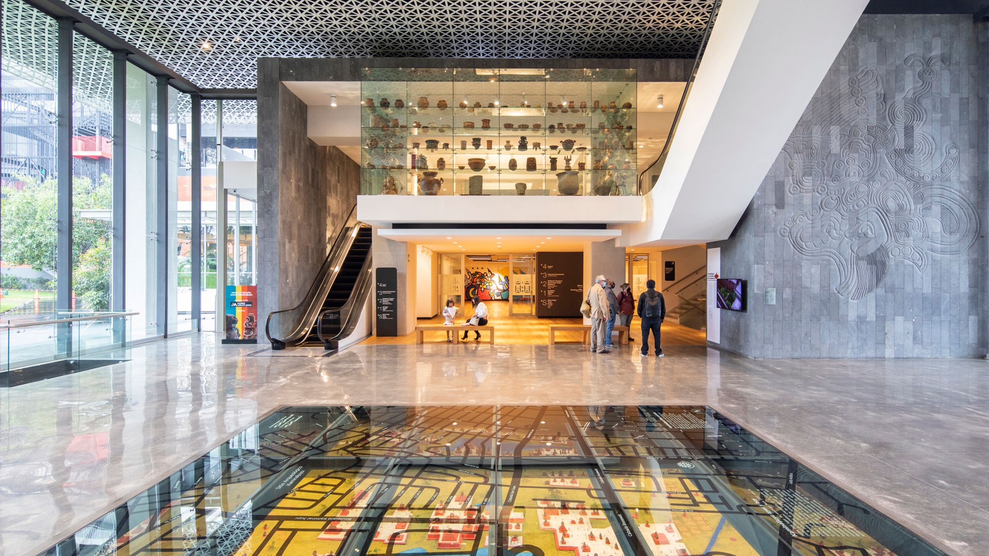 A large room with glass walls and a few people standing in it.