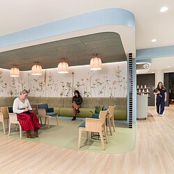 A man and a woman in a room with chairs and a table.