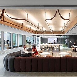 A man and woman sitting at a table in a room with a large screen and a couple of.